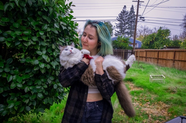 Jamie Marquis and their cat Cleo in their backyard in Sacramento on Dec 4, 2021. Photo by Karlos Rene Ayala for CalMatters